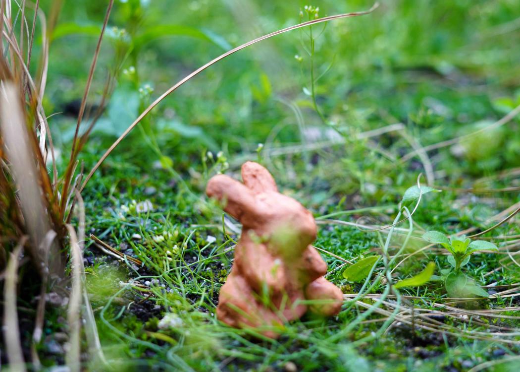 Photo of a small clay bunny sculpture outside in some grass