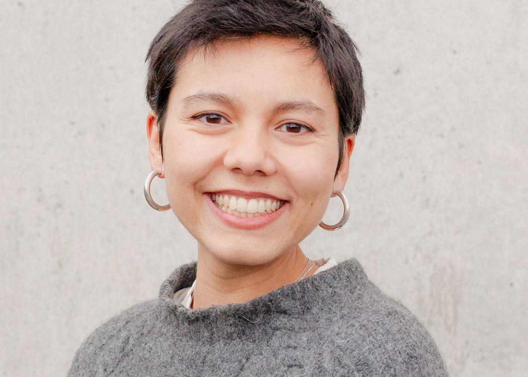 A photograph of a woman with short hair in a gray sweater