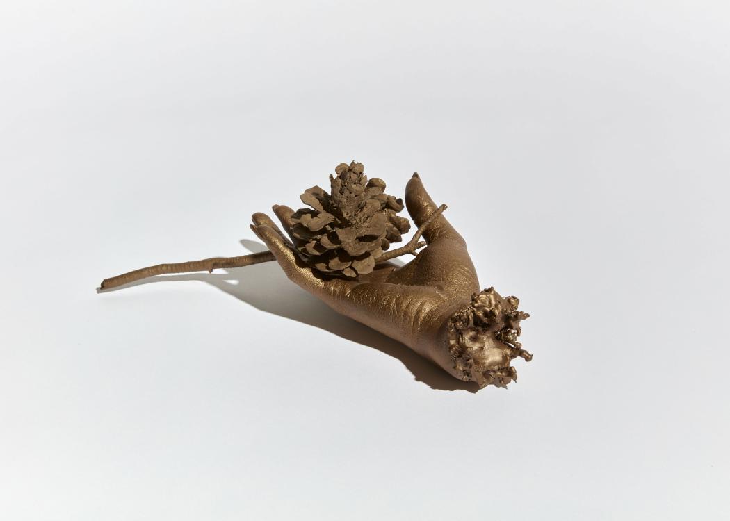 Cast bronze hand holding a pinecone