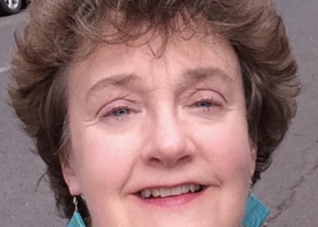 Photo of Ellen Rugg, a woman with short brown hair wearing blue earrings