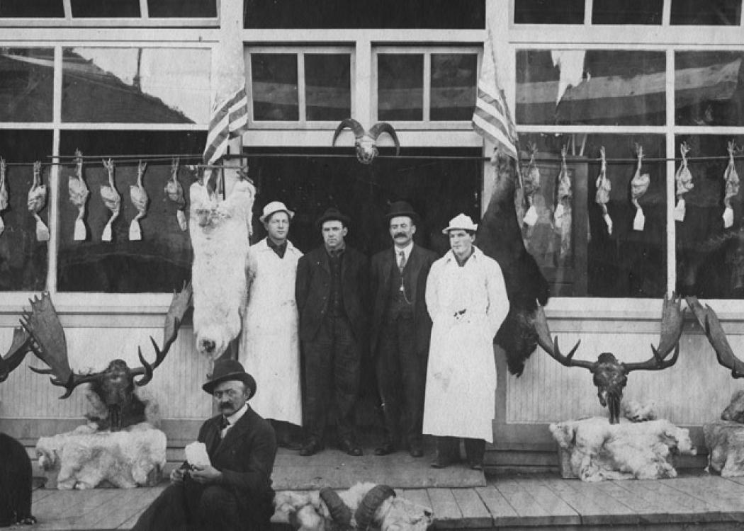 People standing in front of a meatpackers storefront in Seward, Alaska in the early 20th century