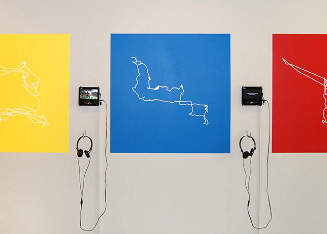 Outlines of geographic areas printed on sheets on a wall next to media players and headphones