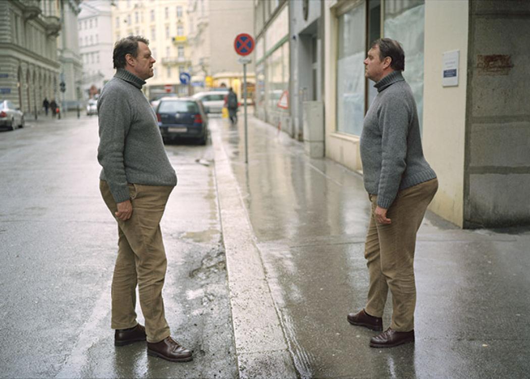 Photo of two identical men with similar clothing facing each other with their eyes closed
