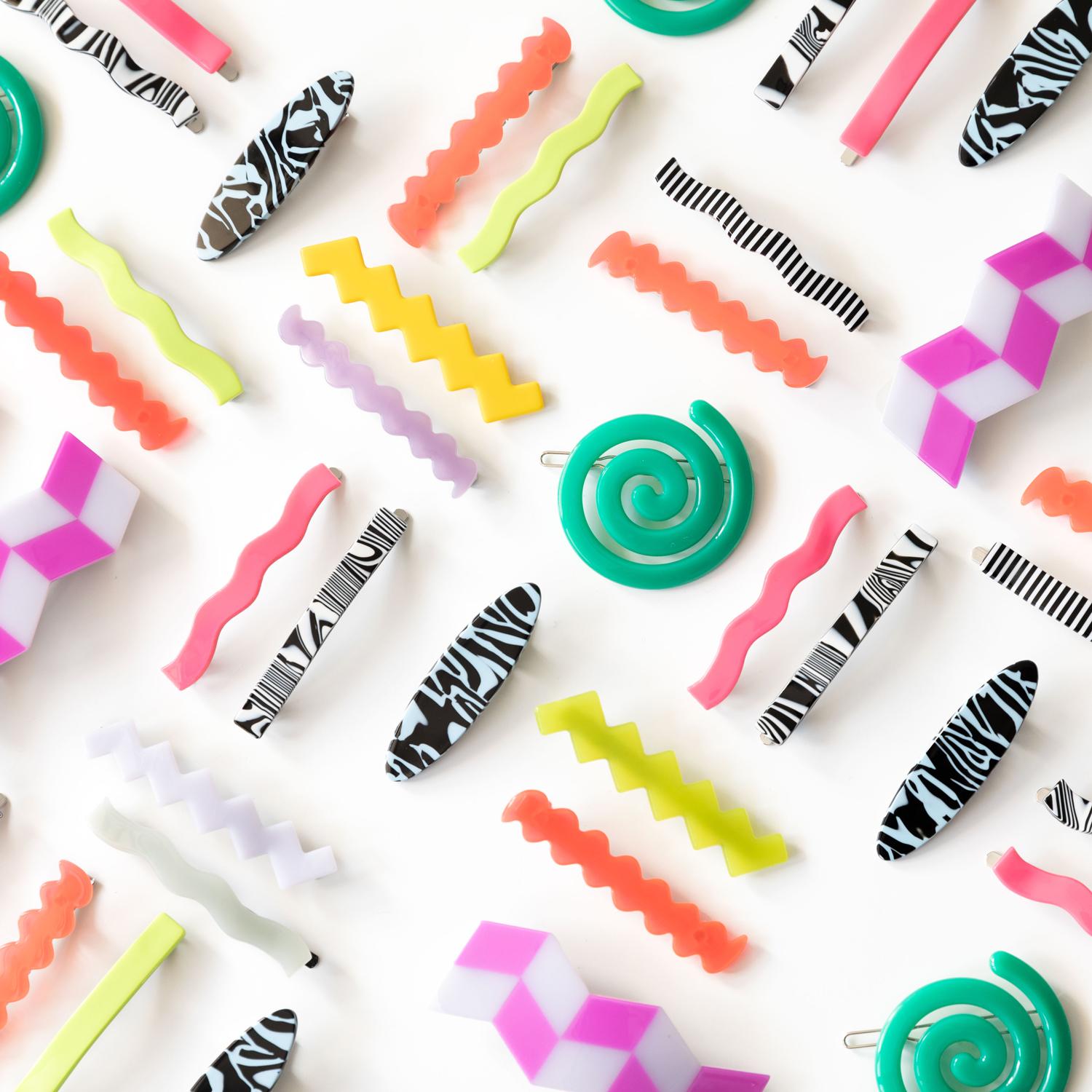 Colorful hair barrettes laid out in a pattern on a white surface