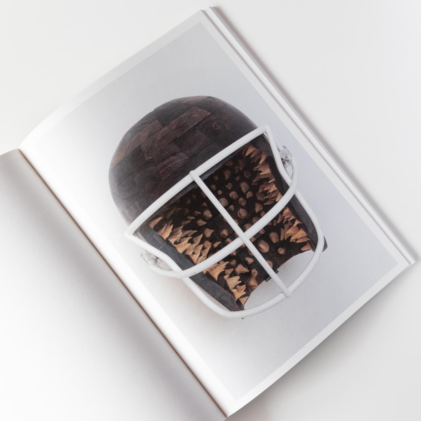 Inside of a book showing a wooden football helmet with spikes inside