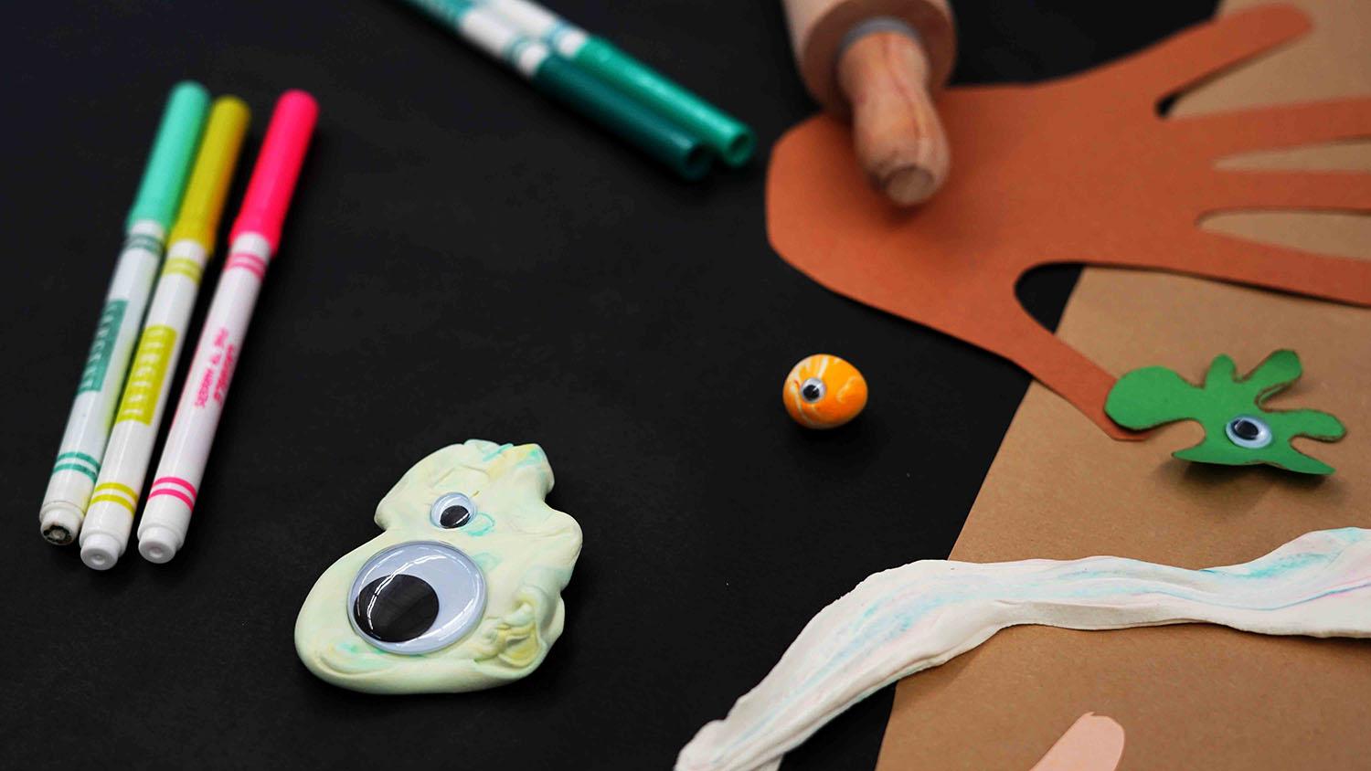 A 'germ' made of a googly eye on clay with other crafting materials in the background