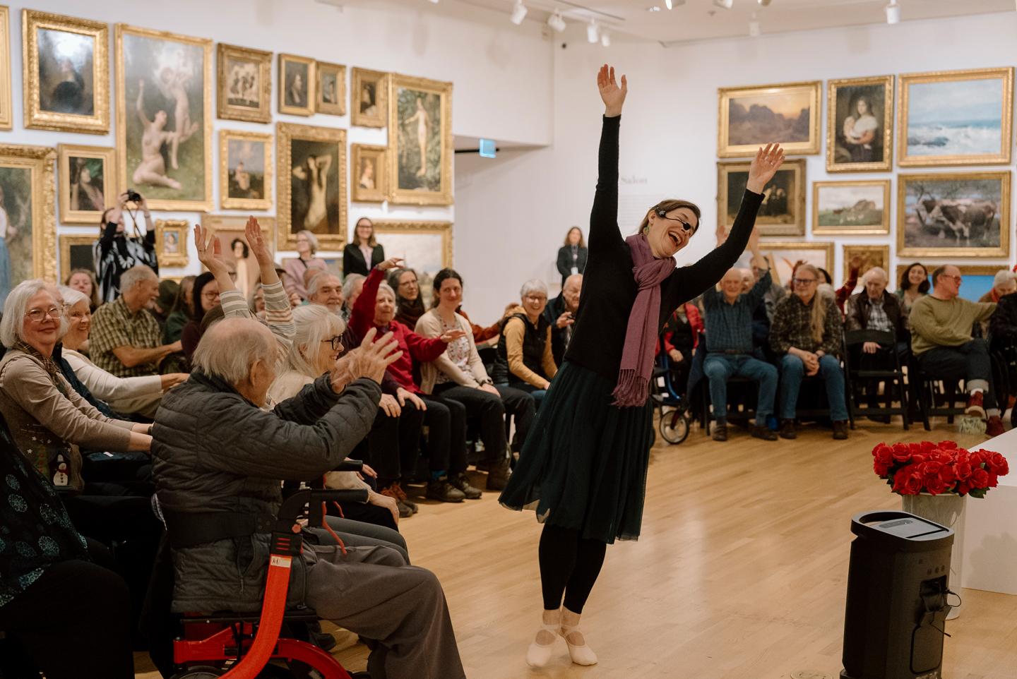 Dr. Julia Becke leads seated movement with a group of participants in the Frye Salon