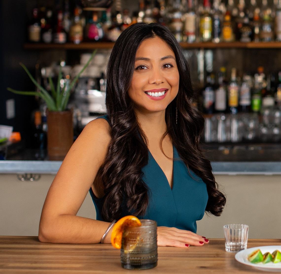 A woman leaning against a bar in a fancy cocktail restaurant setting