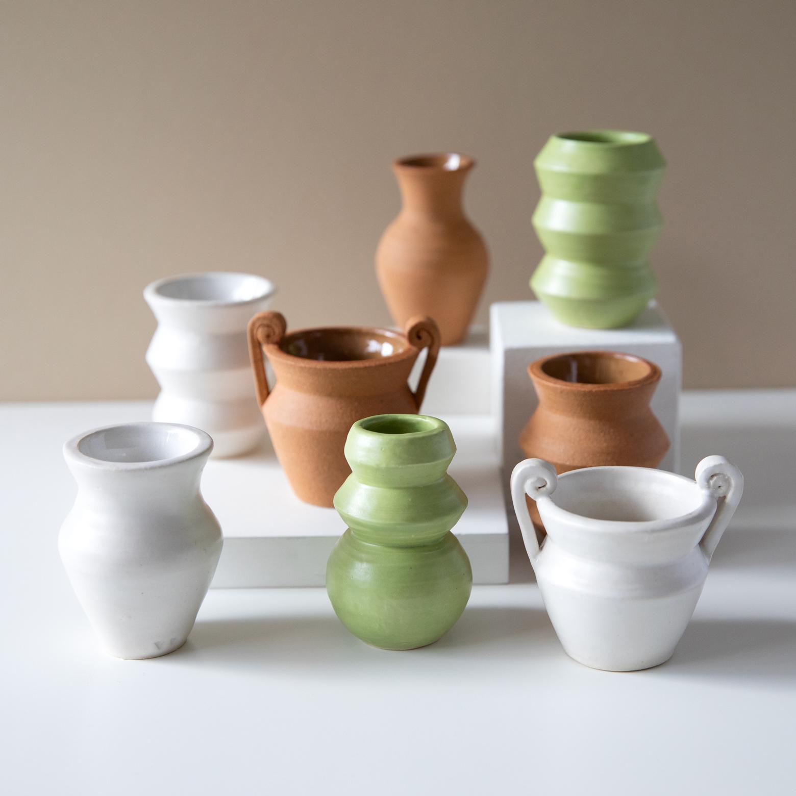 Eight small ceramic vessels in white, brown, or green