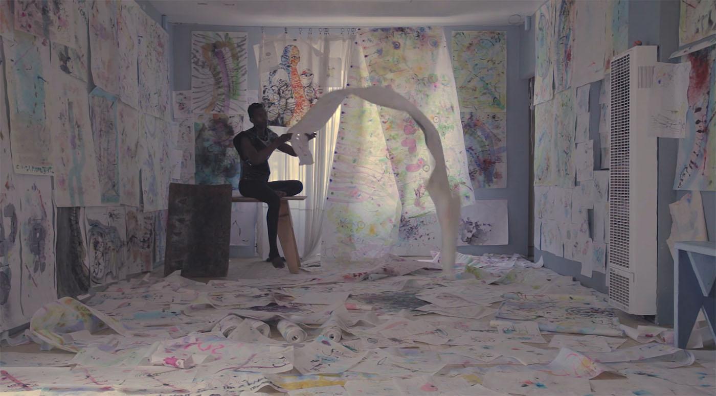 A person sitting on a table in a room whose floor and walls are covered in sheets of paper