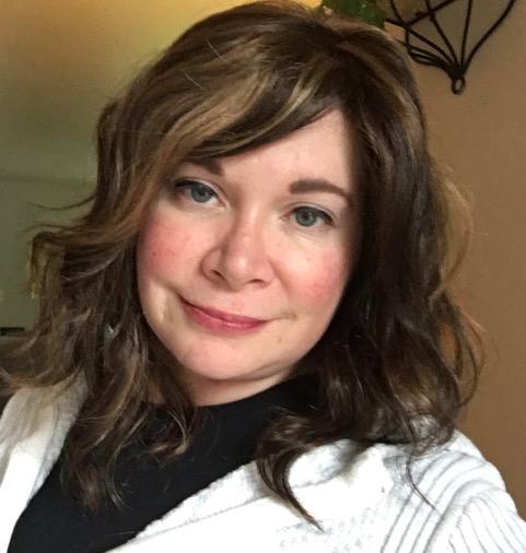 Photo of Jennifer Kulik, a woman with long brown hair wearing a black shirt and white sweater
